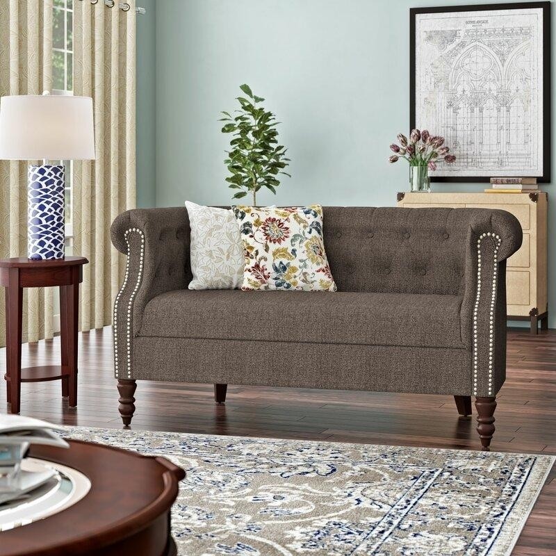 светлбирюзовая гостиная с двухместнвм диванчиком с точеными деревянными ножками, обивкой из льняной ткани и декоративными гвоздиками.jpeg