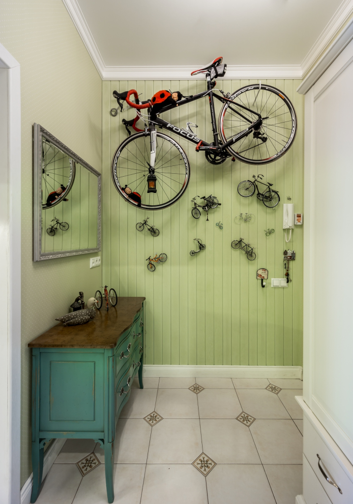 салатовая прихожая с зеленым комодом, прямоугольным зеркалом в раме и декором из велосипедов.jpg