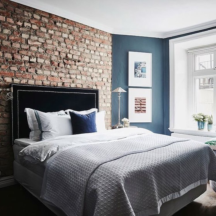 спальня с неокрашенной кирпичной стеной и синей бархатной кроватью.jpg