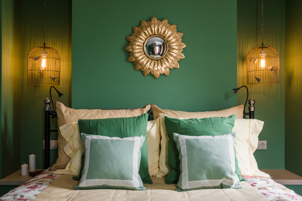 спальня в зеленых тонах со светильниками-клетками и зеркалом в золотой оправе