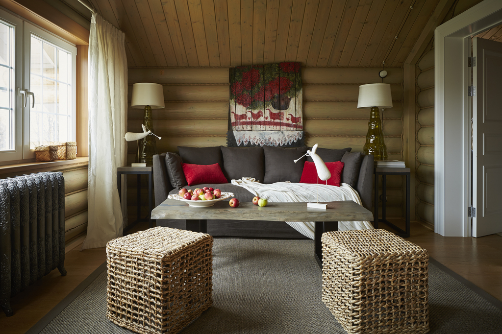 гостиная в деревянном доме с плетеными пуфиками, журнальным столом из массива дерева и коричневым диваном.jpg